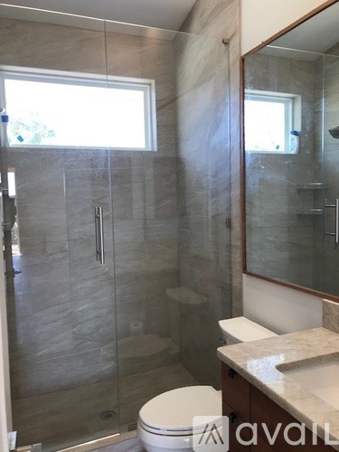 A bathroom with a toilet, sink, and glass shower stall.
