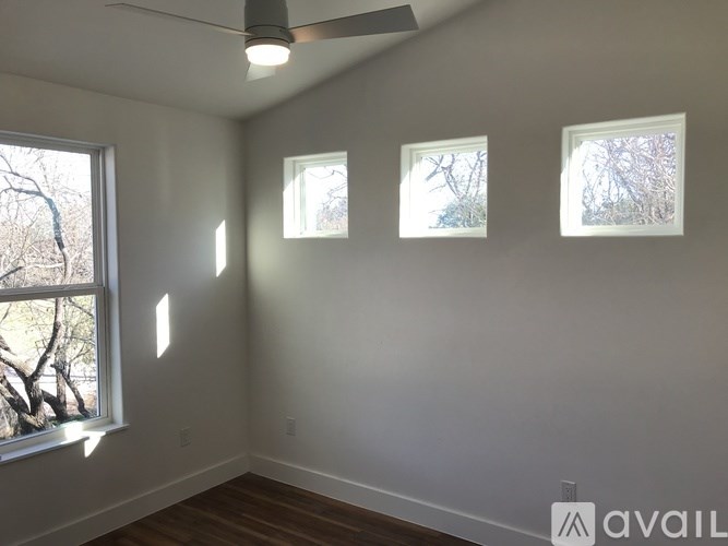 Three windows in a room with a ceiling fan.