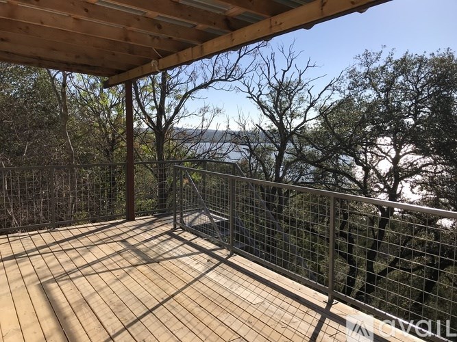 A wooden deck with a metal railing and trees in the background.