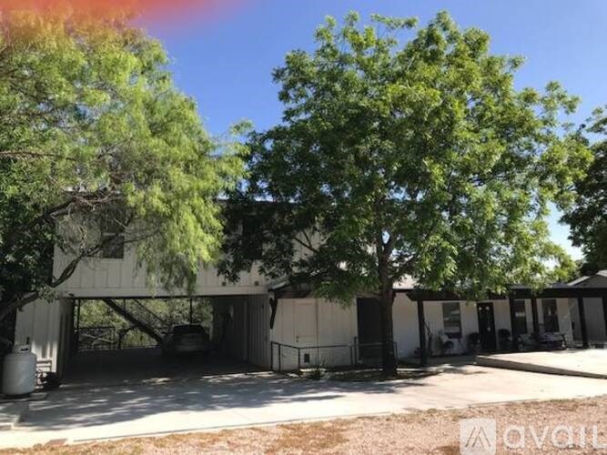 A large white building with a carport and trees in front.