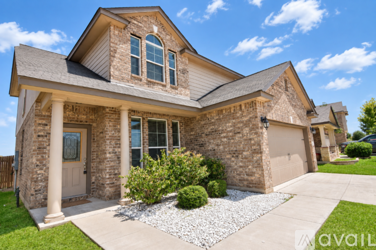 A house with a white garage door is in front of a house with a brown roof.