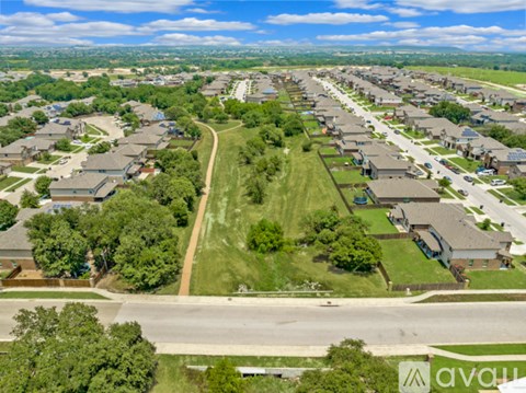 A bird's eye view of a residential area with houses, roads, and a swimming pool.