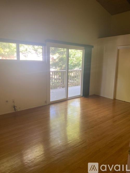 A room with wooden flooring and a sliding glass door.