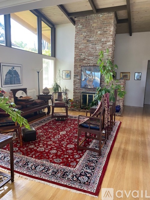 A living room with a red rug and a fireplace.