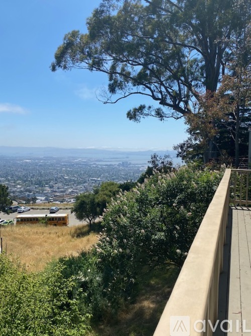 A view from a high vantage point overlooking a cityscape with a clear blue sky and some greenery.