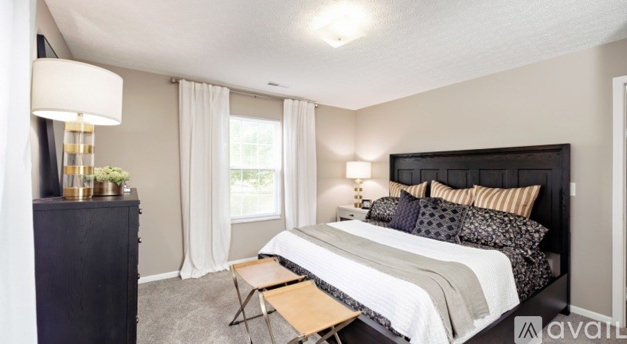 A bedroom with a large bed and a nightstand with a lamp.