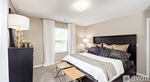 A bedroom with a large bed and a nightstand with a lamp.