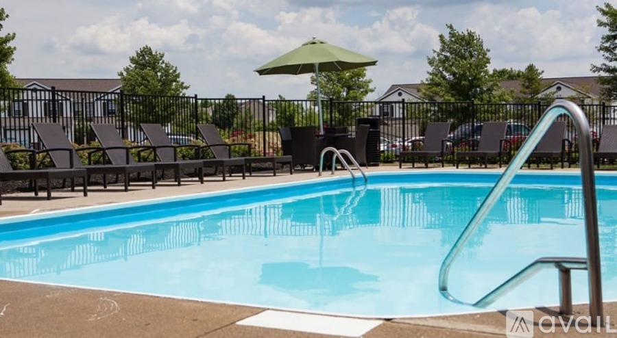 A pool with a slide and chairs around it.