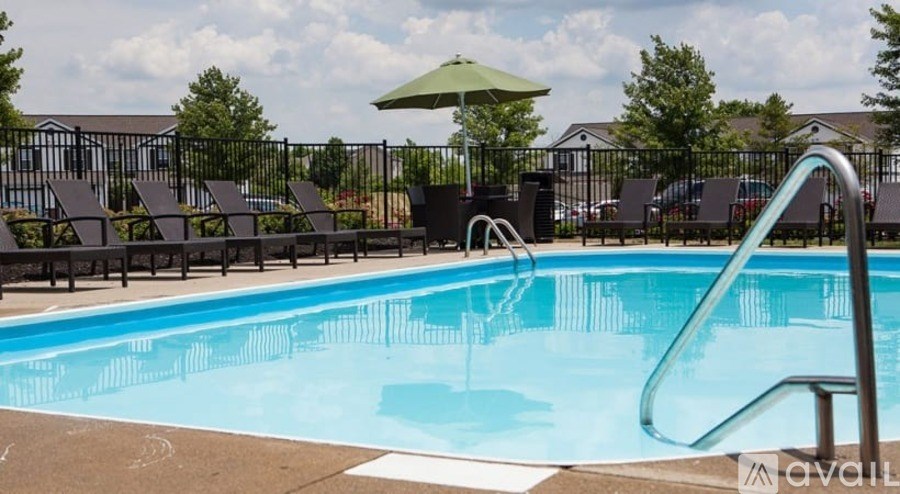 A pool with a slide and chairs around it.