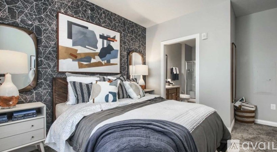 A bedroom with a large bed, a nightstand with a lamp, and a painting on the wall.