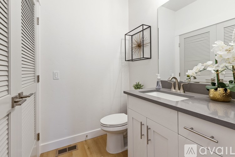 A bathroom with a toilet, sink, and mirror.