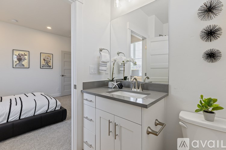 A bathroom with a sink, mirror, and a bed.