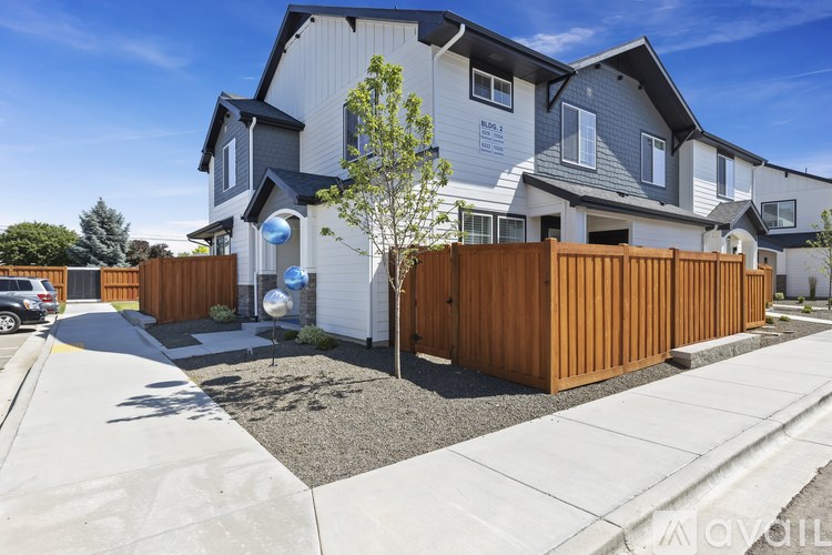 A modern house with a grey and white exterior and a wooden fence.