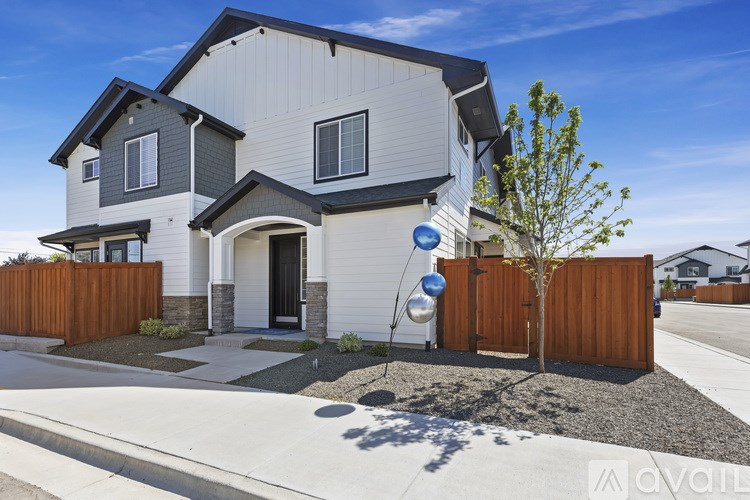 A modern house with a grey and white exterior and a brown fence.