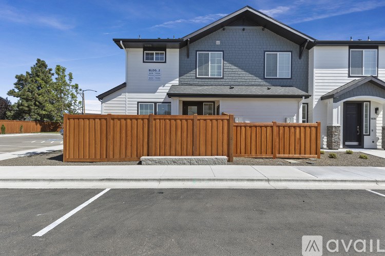 A modern house with a grey roof and a wooden fence in front.