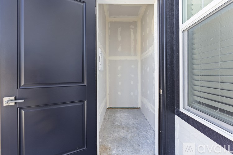 A black door is open to a hallway with a window on the right.