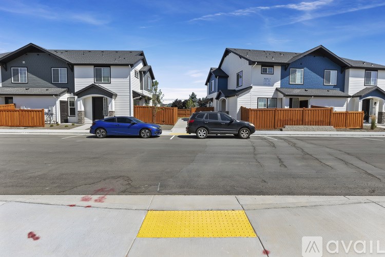 Two cars are parked in a parking lot in front of a row of houses.