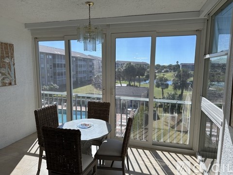 A balcony with a table and chairs overlooking a pool and a building.