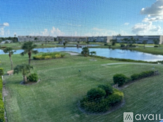 A grassy field with a body of water and a bridge in the distance.