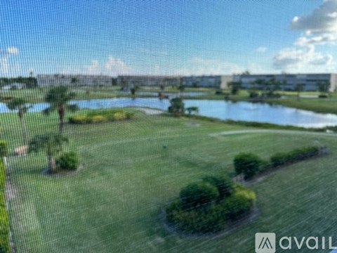 A grassy field with a body of water and a bridge in the distance.