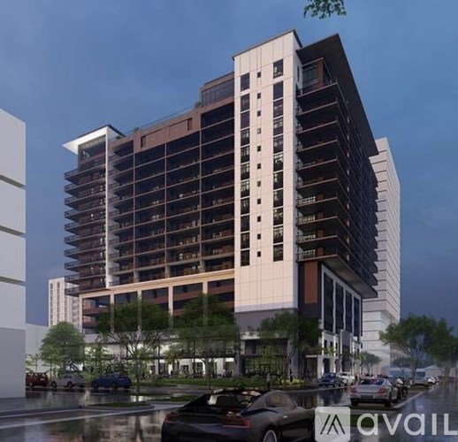 A modern multi-story building with a parking lot in front.