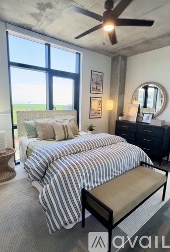 A bedroom with a large bed, a bench, and a ceiling fan.