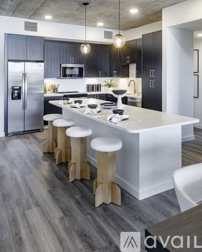 A modern kitchen with a white island and wooden stools.