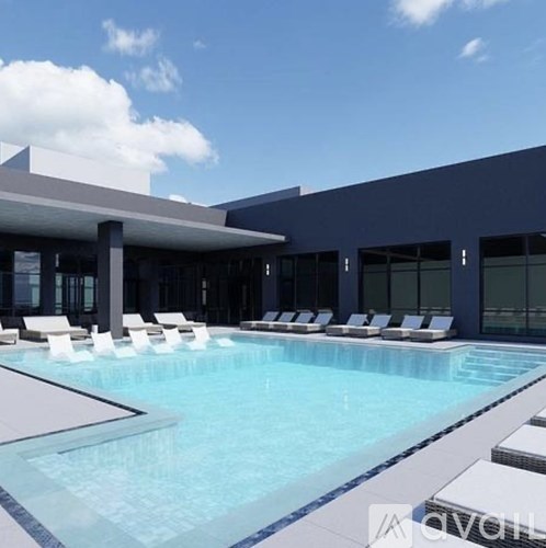 A swimming pool with lounge chairs and a modern building in the background.