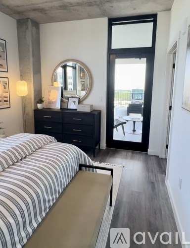 A bedroom with a bed, dresser, mirror, and sliding glass doors.