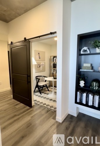 A room with a brown door and a shelf with books and a plant.