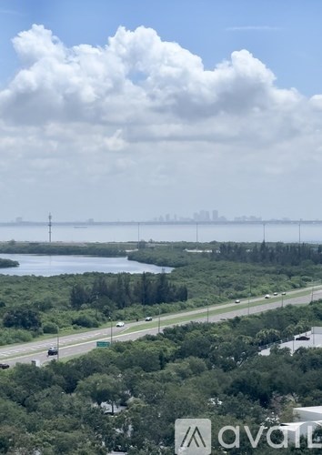 A view of a highway with trees and a body of water in the distance.