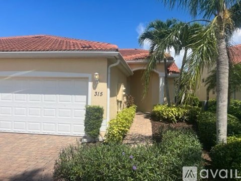 A house with a white garage door and a palm tree in front.