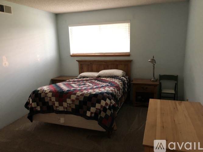 A bedroom with a bed, nightstand, and chair.
