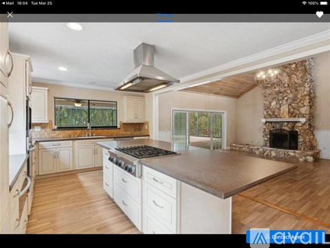 A modern kitchen with white cabinets and a stone fireplace.