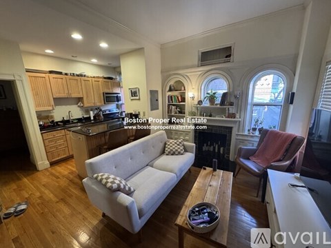 A living room with a couch, a coffee table, and a fireplace.