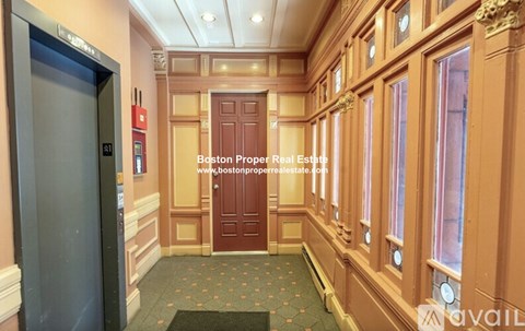 A hallway with a red door and a green doormat.