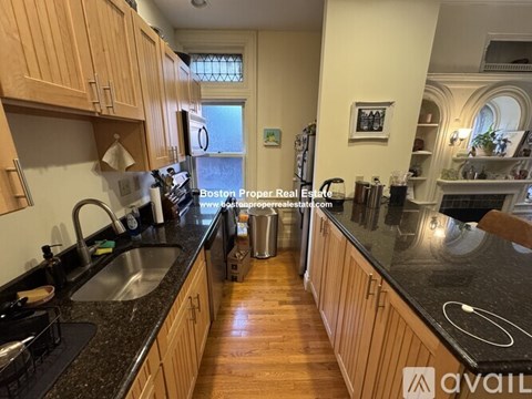 A kitchen with wooden cabinets and black countertops.