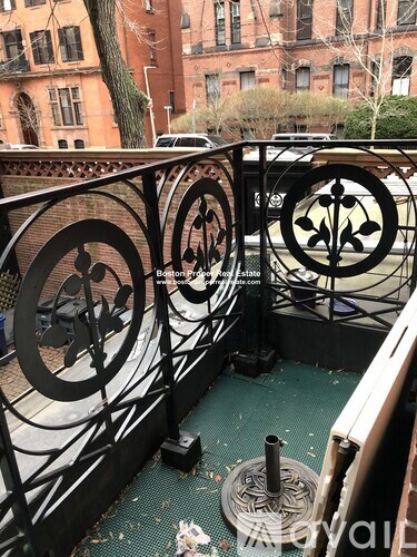 A black wrought iron fence with circular designs is in the foreground of a building.