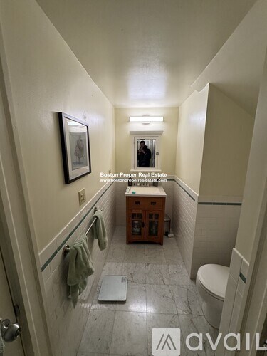 A bathroom with a toilet, sink, and a picture on the wall.