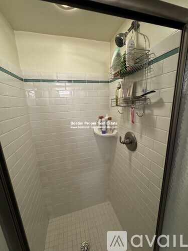A bathroom with a shower and a glass shelf above it.