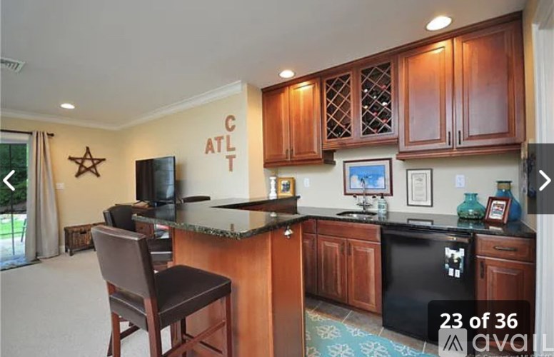 A kitchen with a black fridge and brown chairs.
