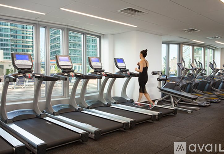 A woman is running on a treadmill in a gym with other treadmills and exercise equipment.