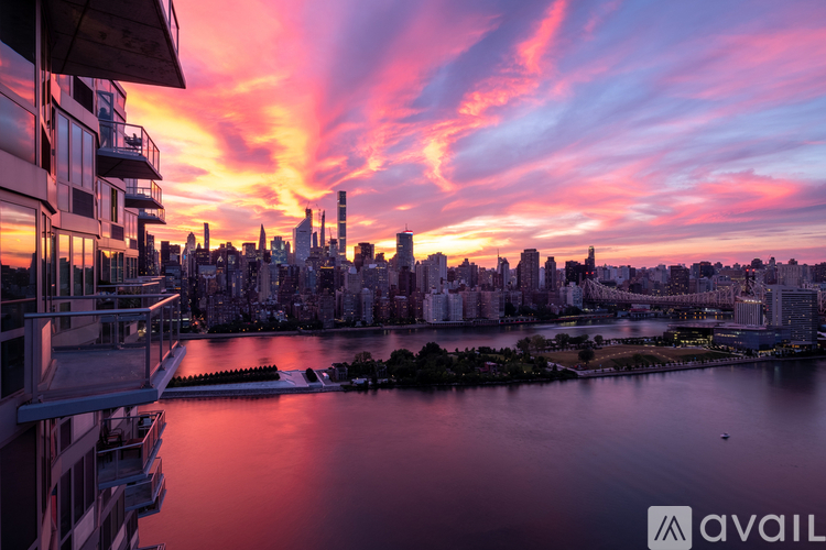 A city skyline at sunset with buildings and a body of water in the foreground.