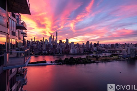 A city skyline at sunset with buildings and a body of water in the foreground.