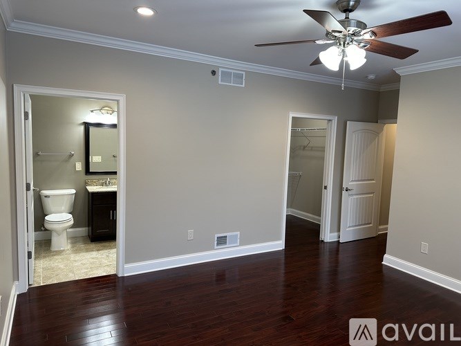 A room with a ceiling fan and a toilet visible through a door.