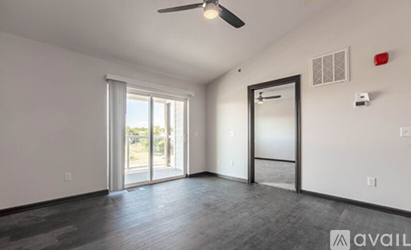 A room with a ceiling fan and sliding glass doors.