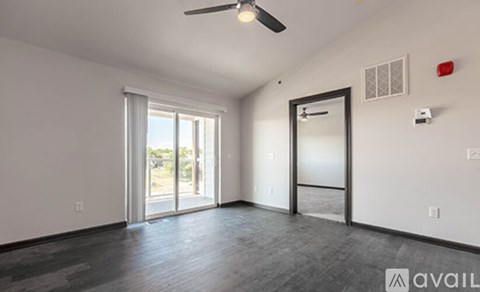 A room with a ceiling fan and sliding glass doors.