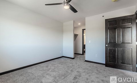 A room with a ceiling fan and a door on the right side.