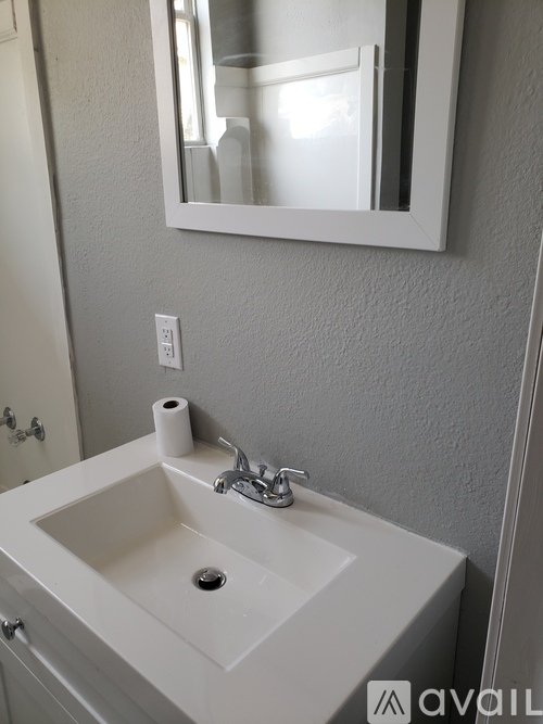 A white sink with a silver faucet and a mirror above it.