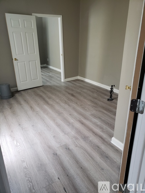 A room with a white door and a grey floor.